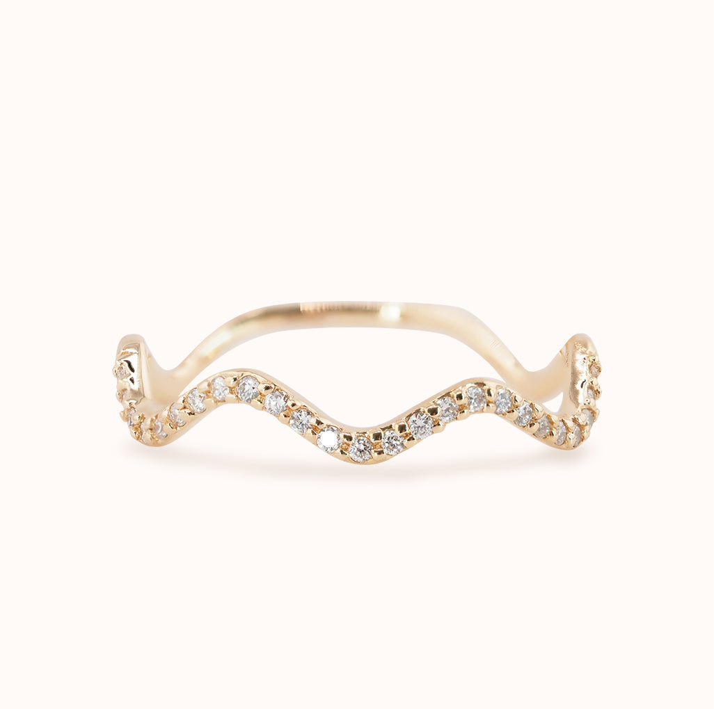 A gold band ring with a wave-like design, set with lab-grown diamonds.